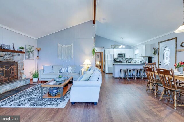 living room with vaulted ceiling, hardwood / wood-style floors, and a stone fireplace