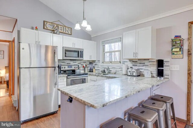 kitchen featuring lofted ceiling, light hardwood / wood-style floors, stainless steel appliances, kitchen peninsula, and white cabinets