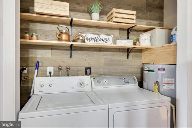 laundry room with washing machine and dryer, wood walls, and electric water heater