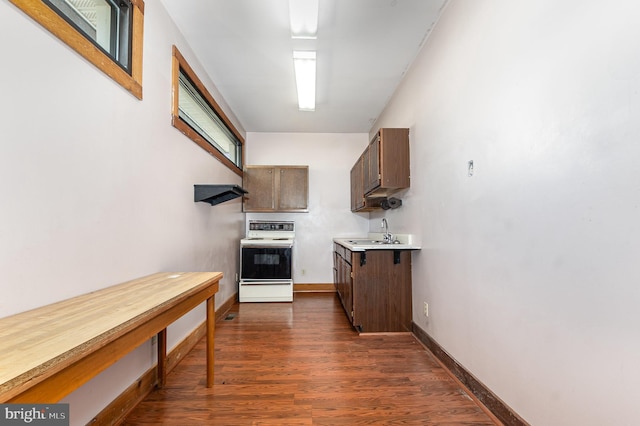 kitchen with electric range, dark wood-type flooring, a sink, baseboards, and light countertops