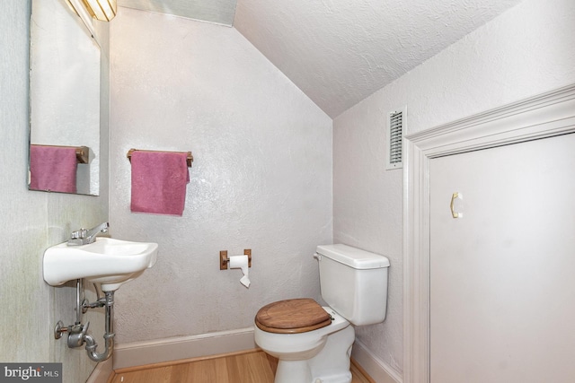 half bathroom featuring toilet, baseboards, vaulted ceiling, and wood finished floors