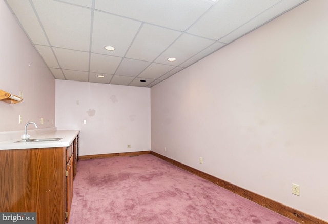 interior space with a paneled ceiling, recessed lighting, light colored carpet, a sink, and baseboards