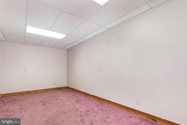 empty room featuring carpet floors, a paneled ceiling, and baseboards