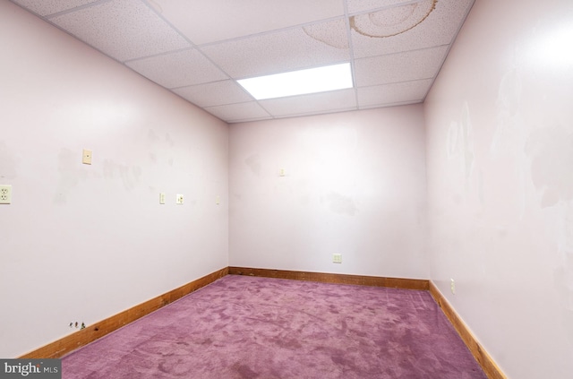 carpeted empty room with a drop ceiling and baseboards