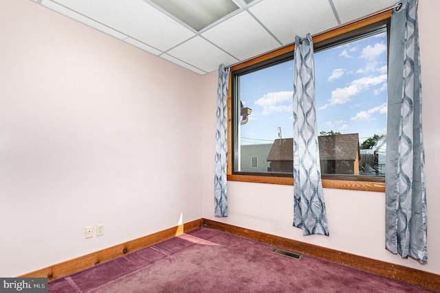 spare room featuring carpet floors, a drop ceiling, visible vents, and baseboards