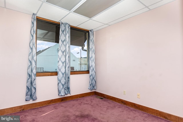 carpeted spare room featuring a drop ceiling, visible vents, and baseboards