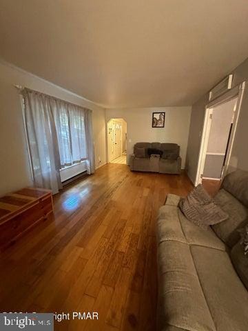 living room with wood-type flooring and a baseboard heating unit