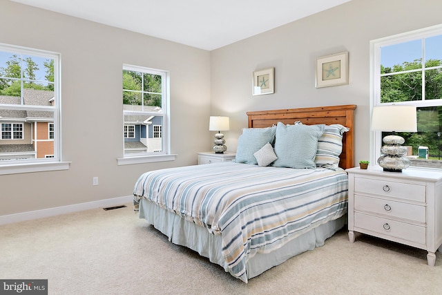 bedroom with multiple windows and light colored carpet