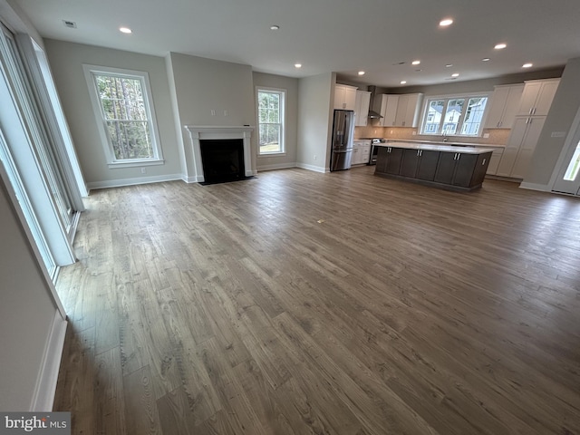 kitchen with a kitchen island, wall chimney exhaust hood, white cabinetry, hardwood / wood-style flooring, and stainless steel appliances