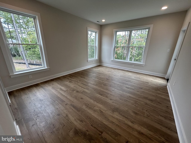 unfurnished room with a healthy amount of sunlight and dark hardwood / wood-style flooring