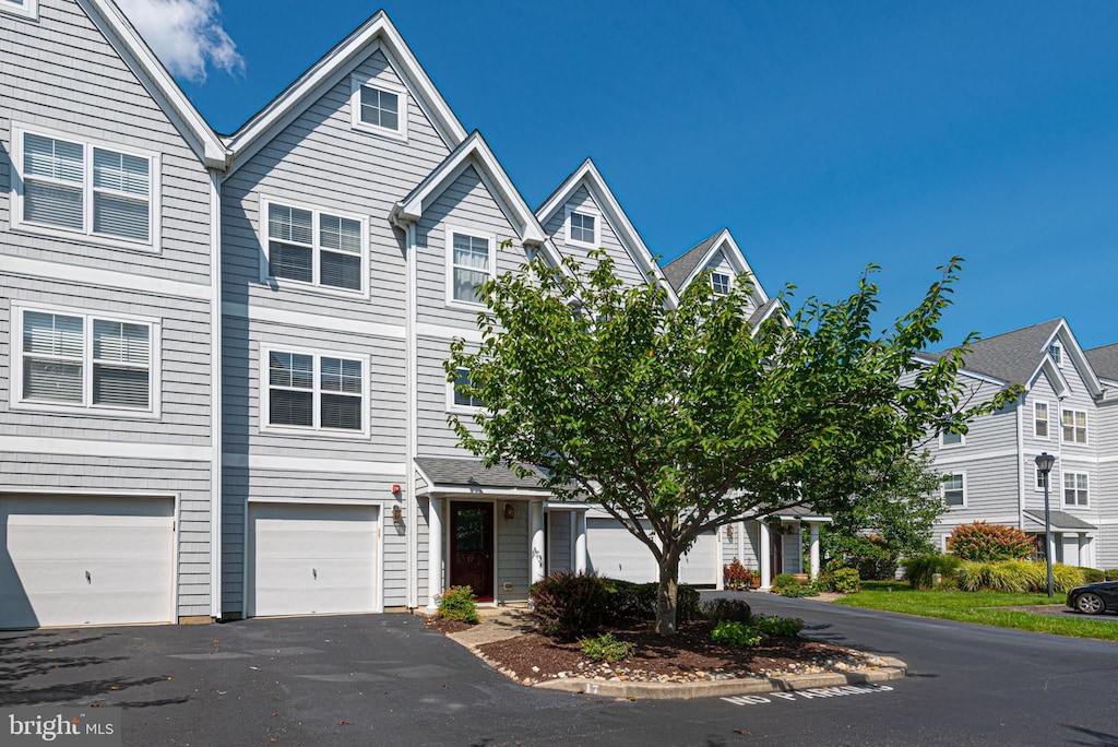 view of property featuring driveway, an attached garage, and a residential view