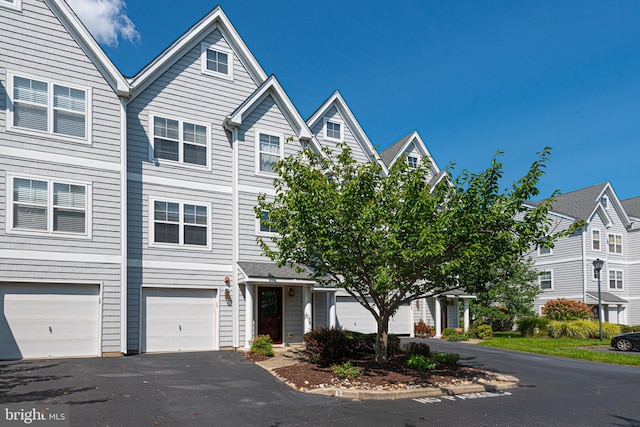 view of property featuring driveway, an attached garage, and a residential view