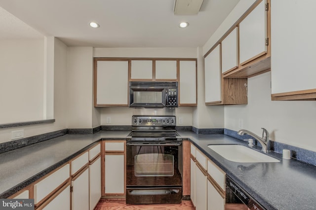 kitchen with black appliances, white cabinetry, and sink