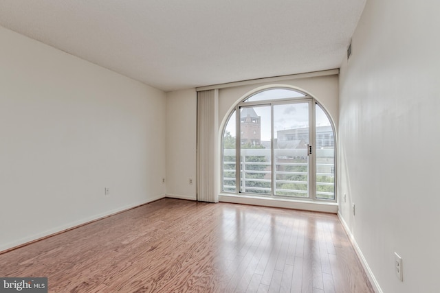 empty room with light wood-type flooring and a textured ceiling