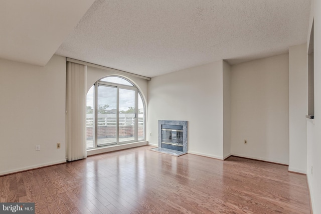 unfurnished living room featuring a textured ceiling, a fireplace, and light wood-type flooring