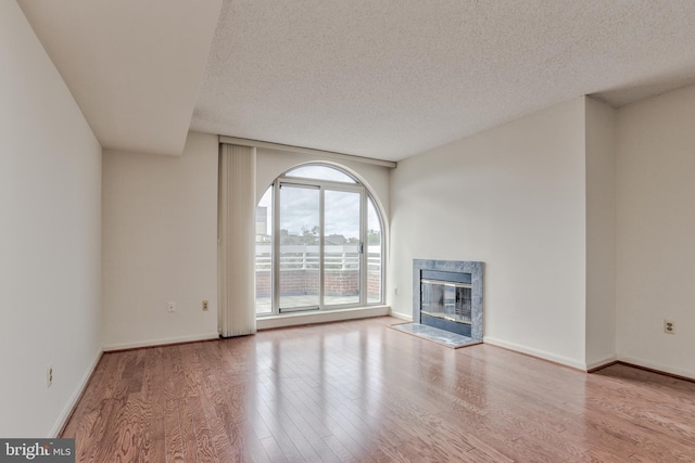 unfurnished living room featuring a textured ceiling, light wood-type flooring, and a premium fireplace