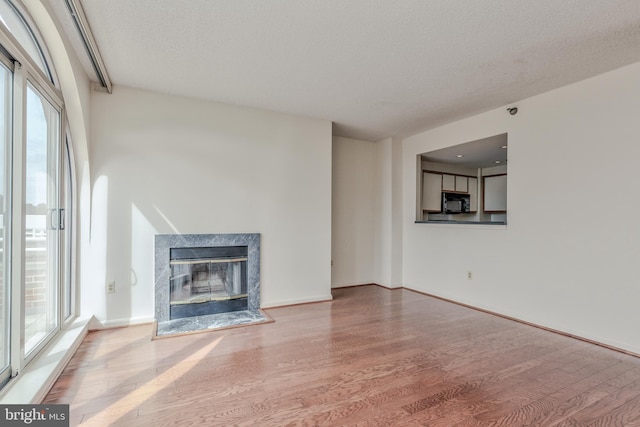 unfurnished living room with a wealth of natural light, a premium fireplace, and hardwood / wood-style floors