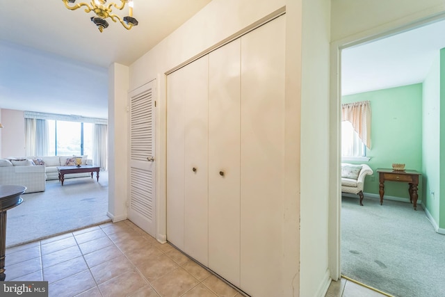 130 Slade Ave Unit 213, Pikesville, MD 21208 - hallway with an inviting chandelier, light carpet, light tile patterned flooring, and baseboards