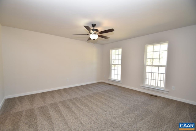 empty room with ceiling fan, carpet floors, visible vents, and baseboards