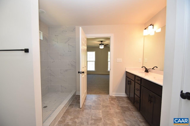 bathroom featuring a sink, a tile shower, baseboards, and double vanity