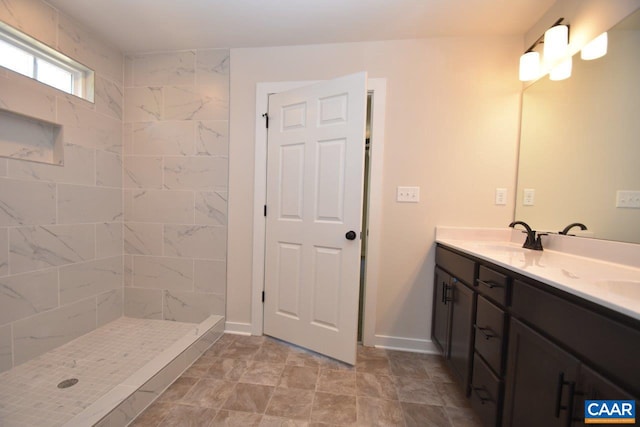 bathroom with double vanity, a shower stall, baseboards, and a sink