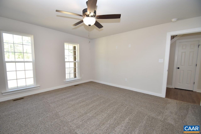 empty room with visible vents, dark carpet, and baseboards