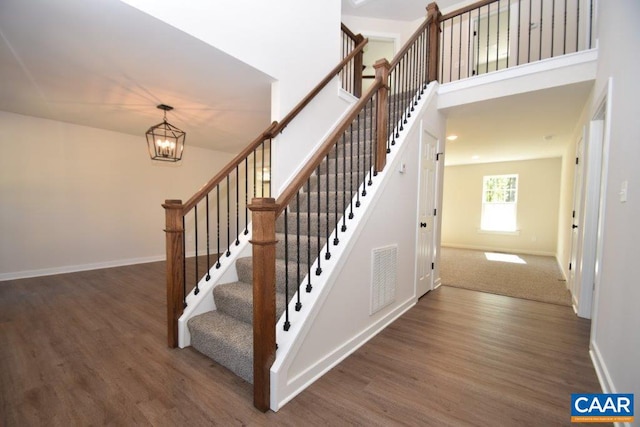 staircase featuring baseboards, visible vents, and wood finished floors