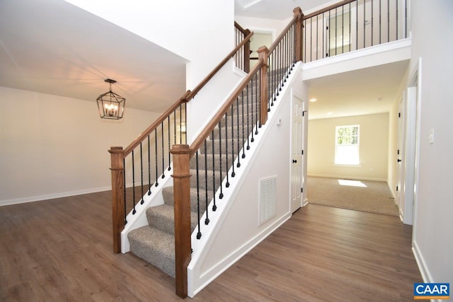 staircase featuring wood finished floors, visible vents, and baseboards