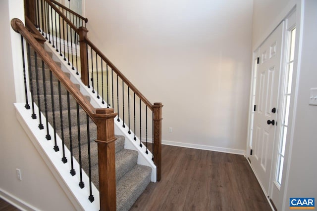 foyer featuring a towering ceiling, dark wood-style floors, baseboards, and a wealth of natural light