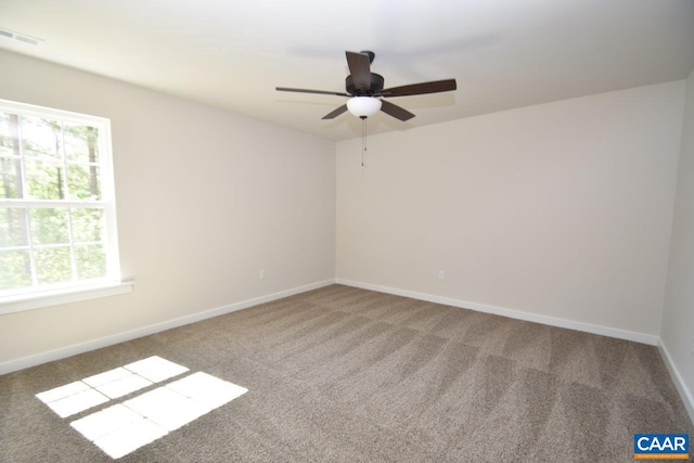 carpeted spare room with baseboards, visible vents, and a ceiling fan