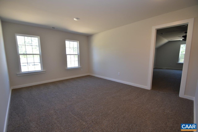 spare room with a ceiling fan, dark carpet, and baseboards