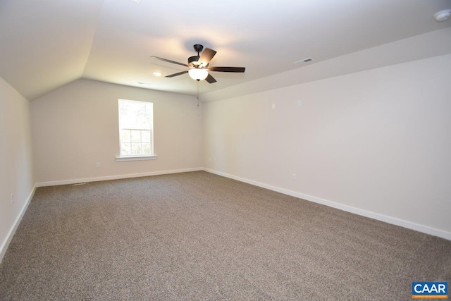 additional living space featuring carpet floors, visible vents, a ceiling fan, vaulted ceiling, and baseboards