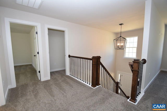 hallway featuring a chandelier, carpet flooring, visible vents, an upstairs landing, and baseboards