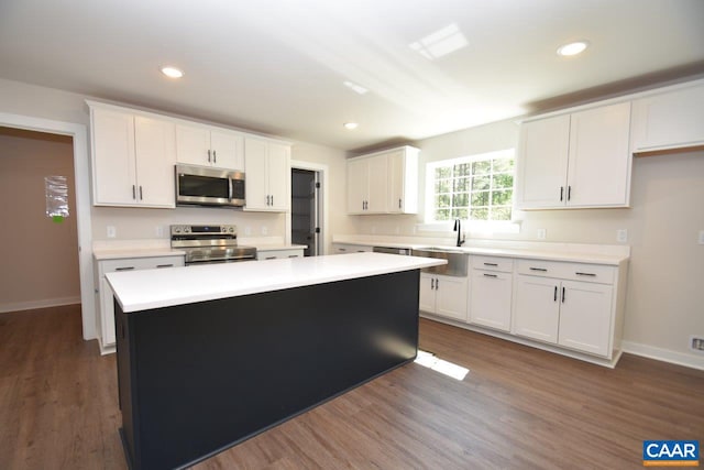 kitchen with appliances with stainless steel finishes, a center island, white cabinets, and light countertops