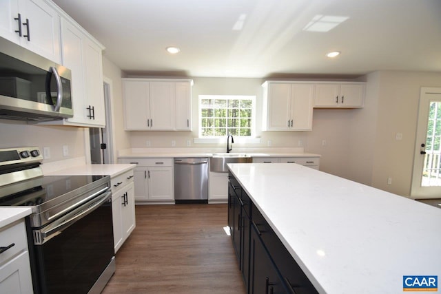 kitchen with stainless steel appliances, dark cabinetry, light countertops, and white cabinets