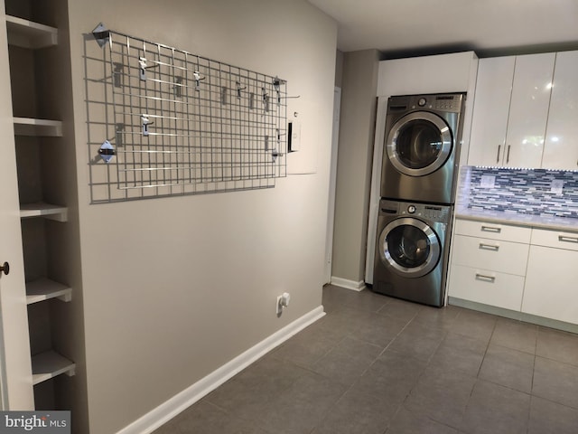 laundry room with dark tile patterned flooring and stacked washer / dryer