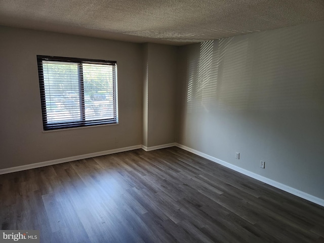 spare room featuring a textured ceiling and dark hardwood / wood-style flooring