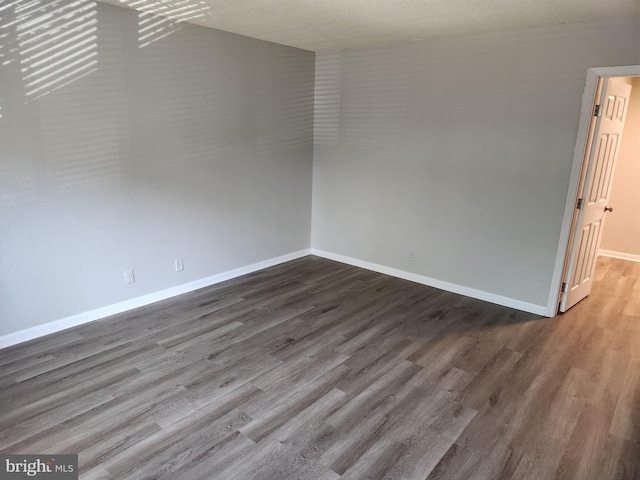 empty room with a textured ceiling, vaulted ceiling, and hardwood / wood-style floors