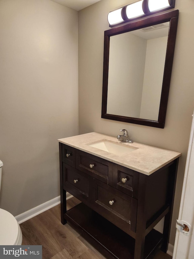 bathroom featuring vanity, toilet, and hardwood / wood-style flooring