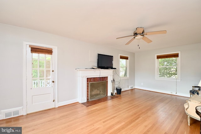 living room with a fireplace, light hardwood / wood-style floors, and a healthy amount of sunlight