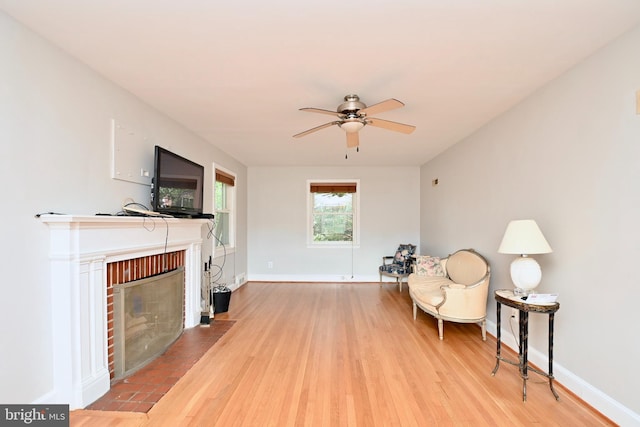 sitting room with ceiling fan, a fireplace, and light hardwood / wood-style floors