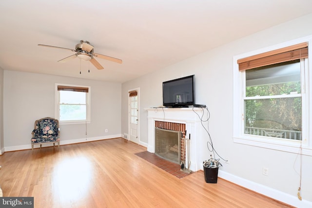 unfurnished living room featuring ceiling fan, light wood-type flooring, and a brick fireplace