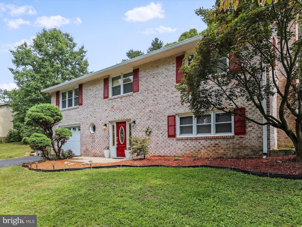 view of front of home with a garage, a front yard, and brick siding