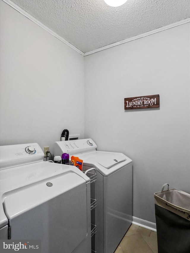 clothes washing area featuring a textured ceiling, tile patterned flooring, laundry area, baseboards, and washer and clothes dryer