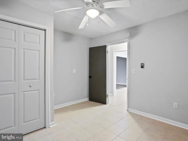 unfurnished bedroom with a ceiling fan, a closet, baseboards, and light tile patterned floors