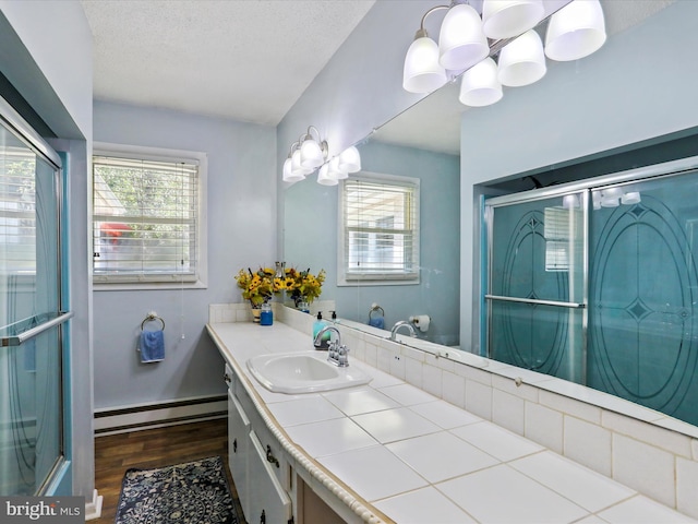 bathroom featuring a baseboard radiator, an enclosed shower, a textured ceiling, vanity, and wood finished floors