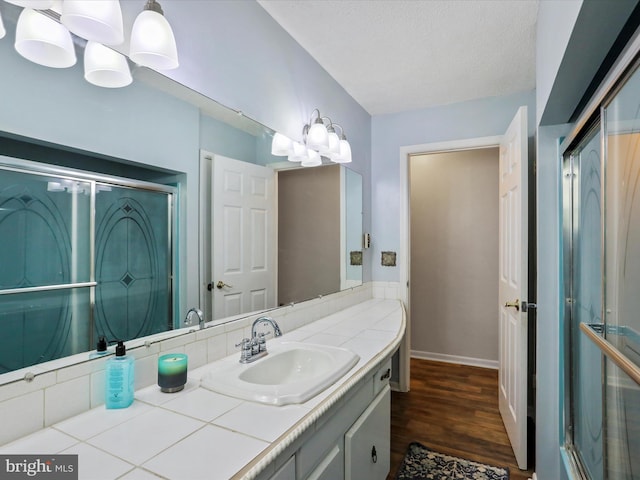 bathroom with a textured ceiling, wood finished floors, vanity, and baseboards