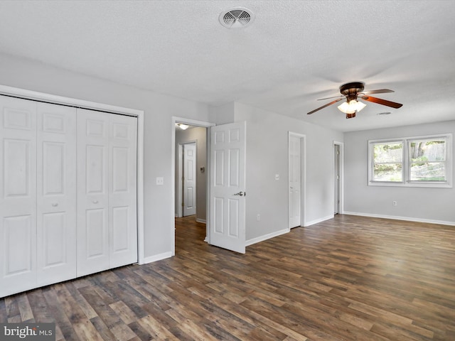 unfurnished bedroom featuring baseboards, visible vents, dark wood finished floors, and a textured ceiling