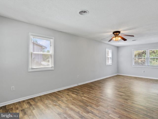 spare room featuring a textured ceiling, baseboards, and wood finished floors