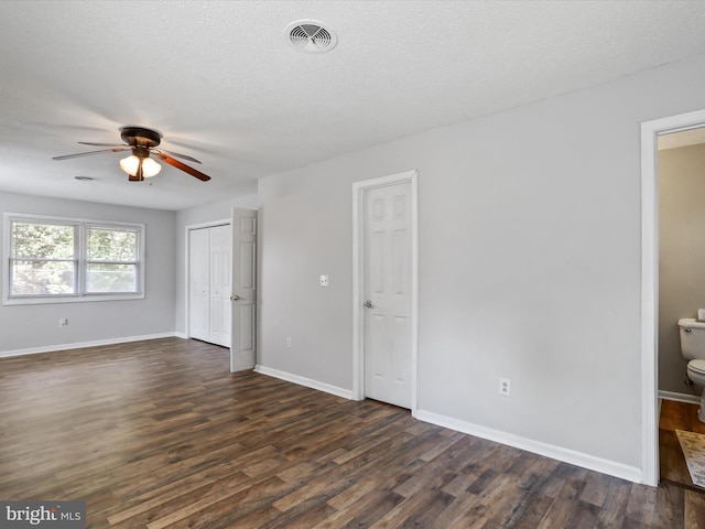 unfurnished bedroom featuring dark wood-style floors, visible vents, a ceiling fan, a textured ceiling, and baseboards